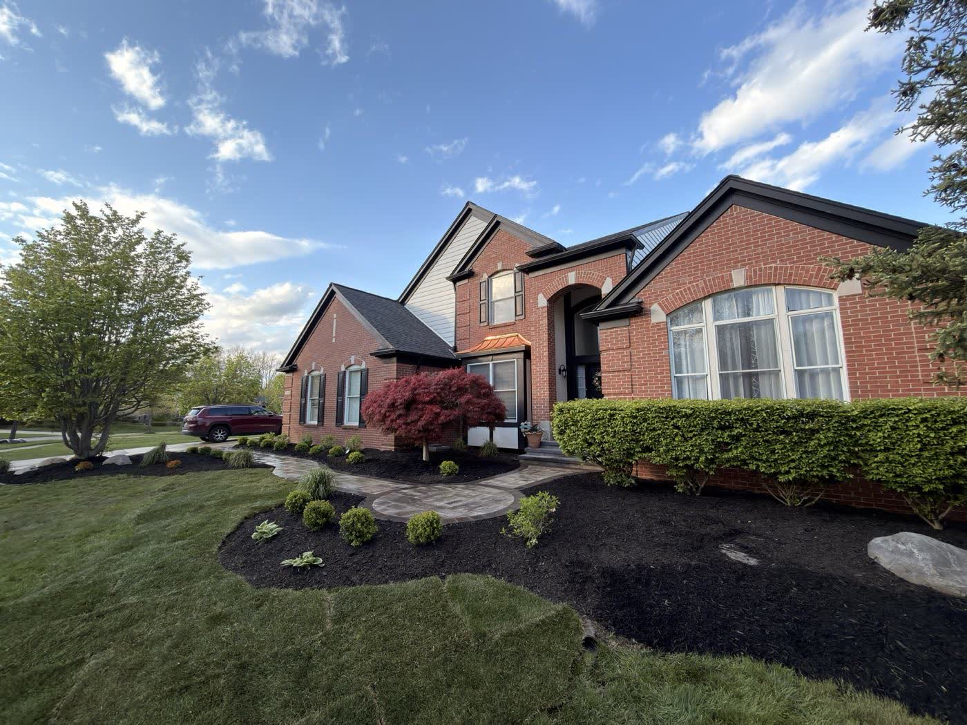 Brick home with new curved mulch beds and a paver walkway