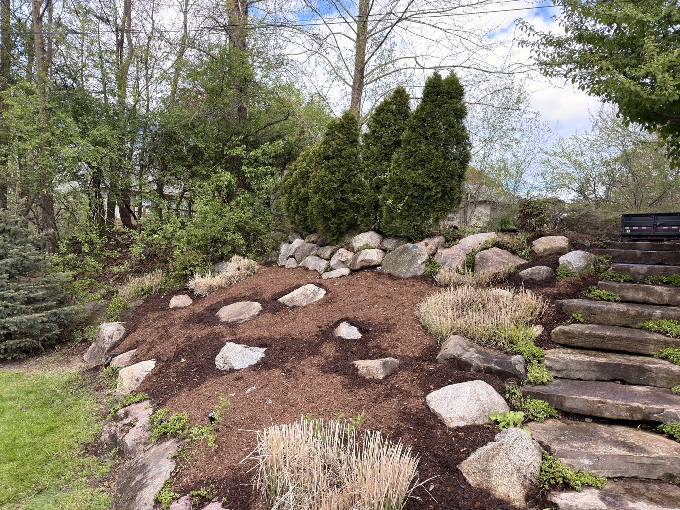 Boulder border and stone steps built into a mulched slope