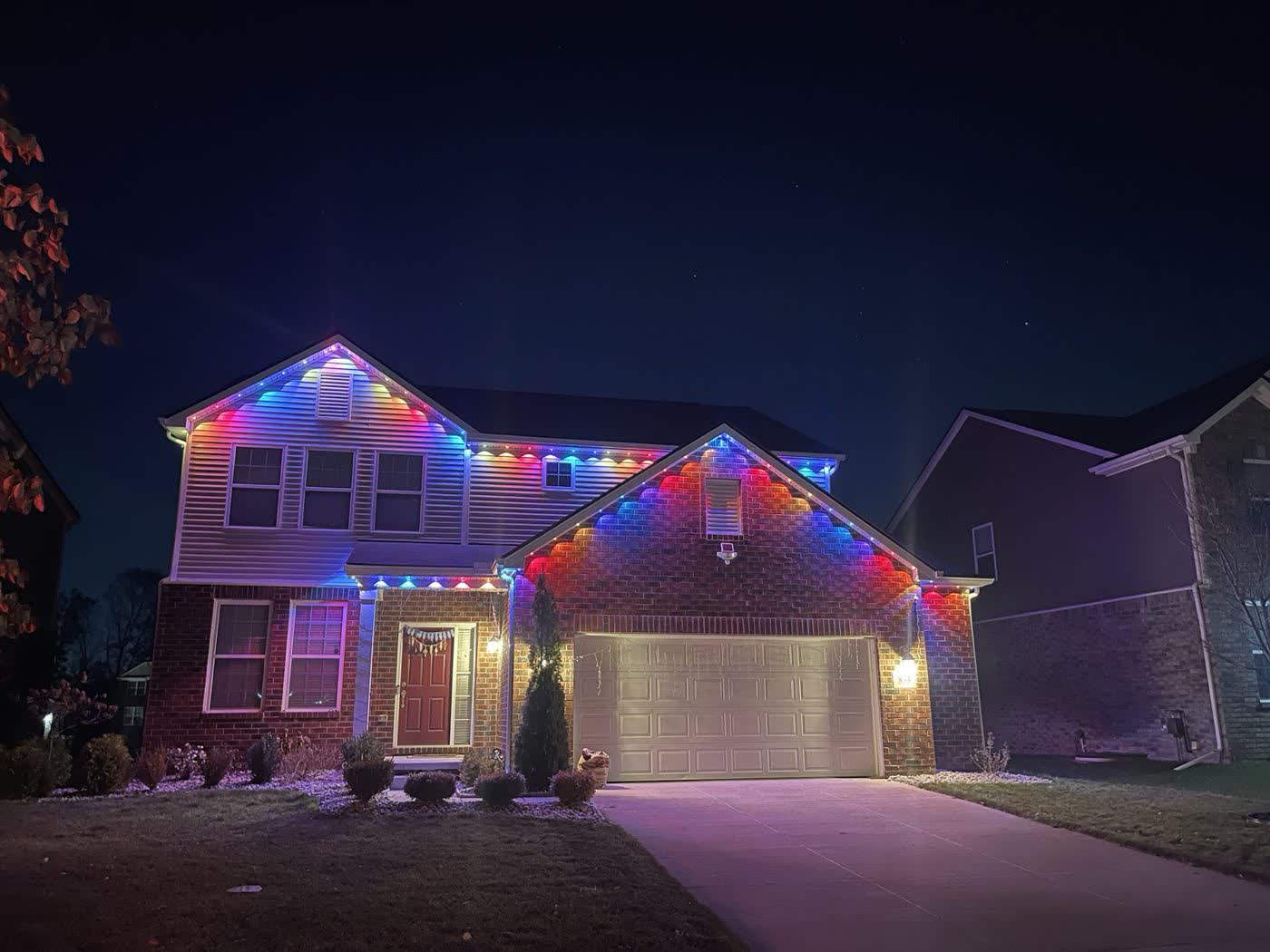 Full color holiday lighting display across a roofline and garage