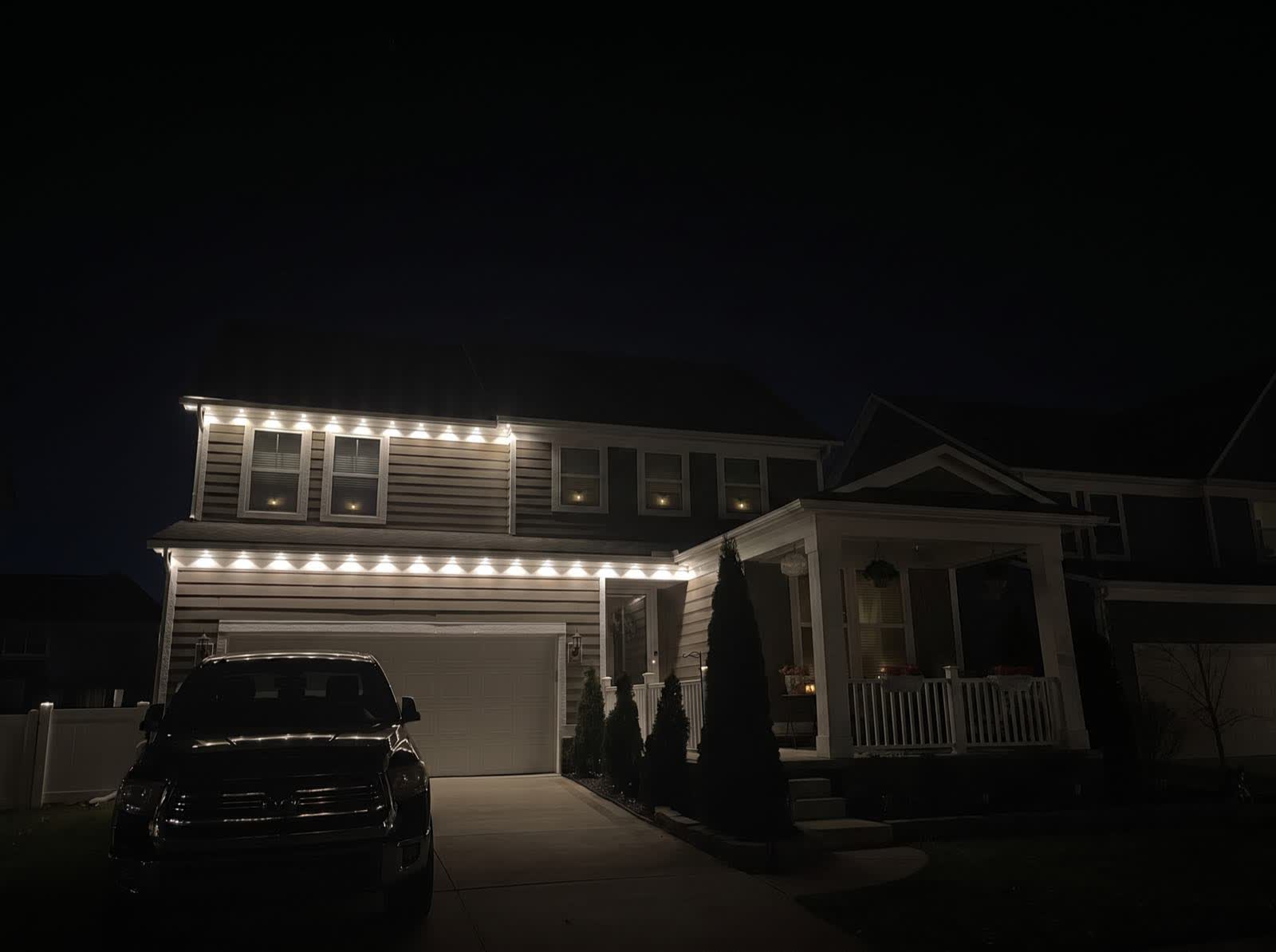 Mid-install: warm white bulbs clipped along the left half of the roofline with the right half still bare